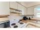 Kitchen featuring older appliances, white cabinetry, and lots of counter space for food preparation; functional and convenient at 315 Magnolia Ave, Anna Maria, FL 34216