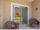 Patio with wicker chairs facing sliding glass doors and landscaped backyard beyond at 3402 Parkridge Cir, Sarasota, FL 34243