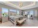 Bright bedroom featuring a tray ceiling, chandelier, large windows, and access to the pool area at 3574 Recurve Cir, Sarasota, FL 34240