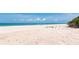 Expansive beach view featuring white sand, clear turquoise water, and an umbrella in the distance under a clear blue sky at 3630 Gulf Of Mexico Dr # 202, Longboat Key, FL 34228