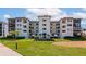 Beautiful condo with a well-manicured lawn, palm trees, and a blue awning covered entryway at 3630 Gulf Of Mexico Dr # 202, Longboat Key, FL 34228