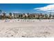 Wide sandy beach with beach chairs, palm trees and buildings in the background at 3806 Gulf Of Mexico Dr # C204, Longboat Key, FL 34228
