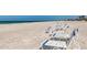 Sandy beach with several white lounge chairs with blue accents and a blue ocean in the background at 3806 Gulf Of Mexico Dr # C204, Longboat Key, FL 34228