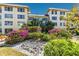 Well maintained landscaping of colorful blooming plants with a grate and multi-story condo buildings in the background at 3806 Gulf Of Mexico Dr # C204, Longboat Key, FL 34228
