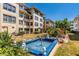 Beautiful courtyard with a fountain, manicured lawn, colorful landscaping, and multi-story condo buildings against a clear blue sky at 3806 Gulf Of Mexico Dr # C204, Longboat Key, FL 34228