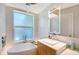 Bright bathroom features a freestanding tub under a window and modern vanity with lighted mirror at 3921 Maravic Pl, Sarasota, FL 34231