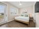 Bright bedroom with wood-look flooring and a white duvet, enhanced by natural light from large windows at 4321 Marina View Way, Cortez, FL 34215