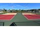 Outdoor pickleball courts featuring vibrant red, yellow and green surfaces with black fencing and clear blue sky overhead at 5213 Bel Air Ave, Sarasota, FL 34234