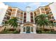 Elegant condo building featuring a grand entrance, lush landscaping, and palm trees at 5450 Eagles Point Cir # 404, Sarasota, FL 34231