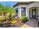 Inviting front entrance with a decorative glass door, arched entryway, and professionally landscaped garden beds at 5740 Eagle Creek Rd, Sarasota, FL 34238