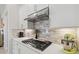 Modern kitchen features stainless steel hood, gas cooktop, white cabinets, and tile backsplash at 5740 Eagle Creek Rd, Sarasota, FL 34238