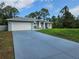 Charming single-story home with a lovely blue exterior, lush yard, and an attached two-car garage and blue driveway at 5849 Wagon Wheel Dr, North Port, FL 34291