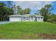 Charming single-story home featuring a well-manicured lawn, lovely blue exterior, and an attached two-car garage at 5849 Wagon Wheel Dr, North Port, FL 34291