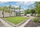 Well-manicured backyard featuring a lush lawn, palm trees, a fire pit, and a screened-in patio, perfect for outdoor activities at 5988 Viola Rd, Venice, FL 34293