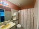 This bathroom features a shower/tub combo, tiled walls, and a large mirror above the sink at 6618 Kenwood Dr, North Port, FL 34287