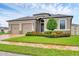 Charming tan home featuring a two-car garage, brick driveway, and beautifully landscaped front yard with a decorative tree at 6636 35Th E Ct, Sarasota, FL 34243