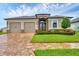 Beautiful tan house with a two-car garage, stone accents, a brick paver driveway, and meticulously landscaped flower beds at 6636 35Th E Ct, Sarasota, FL 34243