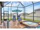 Screened-in pool area featuring a hot tub, lounge chairs, and an umbrella at 6636 35Th E Ct, Sarasota, FL 34243
