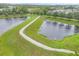 Scenic walking path between two ponds surrounded by lush green grass and neighborhood views at 6636 35Th E Ct, Sarasota, FL 34243