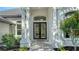 Close-up of the front entrance showcasing the double doors, columns, arched window, and manicured landscaping at 6641 Saint James Xing, University Park, FL 34201