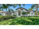 Stunning white home featuring lush landscaping, an arched entrance, tile roof, and beautiful palm trees at 6641 Saint James Xing, University Park, FL 34201