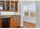 Bar area with custom cabinets, granite countertop, sink, wine cooler, and window with bright natural light at 7081 Grassland Ct, Sarasota, FL 34241