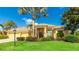 Inviting single-story home featuring lush landscaping, a light yellow exterior, and a tile roof against a bright blue sky at 7081 Grassland Ct, Sarasota, FL 34241