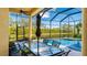 Covered lanai next to the pool with an outdoor dining and seating area overlooking the lake at 7081 Grassland Ct, Sarasota, FL 34241