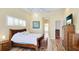 Bright main bedroom with wood floors, white bedding, sunflower art, TV, and custom trim work on the ceiling at 7081 Grassland Ct, Sarasota, FL 34241