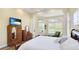 Spacious main bedroom featuring wood floors, white bedding, sitting area, TV and windows for natural light at 7081 Grassland Ct, Sarasota, FL 34241