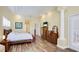 Main bedroom with wood floors, white bedding, custom trim work, sunflower art, and sitting area in the background at 7081 Grassland Ct, Sarasota, FL 34241