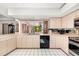 Kitchen with light cabinets, black appliances, and a view of the lanai, creating a bright cooking space at 7615 17Th W Ave, Bradenton, FL 34209