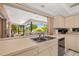 Close-up on the countertop featuring a stainless steel sink, a view into the outdoor lanai, and light-colored cabinetry at 7615 17Th W Ave, Bradenton, FL 34209