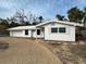 A charming single-story home with white exterior, gravel driveway, and minimal landscaping set against a cloudy sky at 782 Birdsong Ln, Sarasota, FL 34242