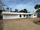 Charming single-story home featuring white paint, a two-car garage, and tropical landscaping with palm trees at 782 Birdsong Ln, Sarasota, FL 34242