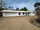 A charming single-story home featuring a light gravel drive and surrounded by vibrant palm trees under a bright, cloudy sky at 782 Birdsong Ln, Sarasota, FL 34242