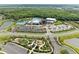 Aerial view of the community clubhouse, pool area, playground, and parking, with a lake and lush greenery in the background at 8264 Summer Night Rd, Sarasota, FL 34241