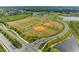 Aerial view of community sports fields, including baseball diamonds, soccer fields, and recreation center with pools and tennis courts at 8264 Summer Night Rd, Sarasota, FL 34241