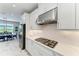 Gourmet kitchen with gas cooktop, stainless hood, white subway tile backsplash, and modern white cabinets at 8264 Summer Night Rd, Sarasota, FL 34241