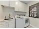 Bright laundry room featuring white cabinetry, granite counters, and modern washer and dryer at 8264 Summer Night Rd, Sarasota, FL 34241