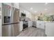 Modern kitchen with stainless steel appliances, decorative backsplash, and wood-look flooring at 946 N Beneva Rd # V26, Sarasota, FL 34232