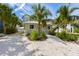 Charming home with a well-manicured yard featuring lush greenery, palm trees, and a crushed shell driveway at 109 Maple Ave, Anna Maria, FL 34216