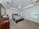 Spacious bedroom featuring a tray ceiling, ceiling fan, and a large window providing natural light at 12682 Shimmering Oak Cir, Venice, FL 34293