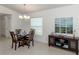 Bright dining room features a modern chandelier and a decorative cabinet with beach-themed artwork at 12682 Shimmering Oak Cir, Venice, FL 34293