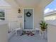 Detailed view of the light blue front door with wreath and matching wicker chairs for welcoming charm at 12682 Shimmering Oak Cir, Venice, FL 34293