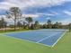 Community tennis court featuring a green and blue playing surface surrounded by a fence at 12682 Shimmering Oak Cir, Venice, FL 34293