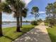 Scenic community walking path along a lake featuring palm trees, a bench and blue skies at 12682 Shimmering Oak Cir, Venice, FL 34293