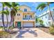 Charming yellow two-story home with balcony, turquoise door, brick driveway, and palm trees at 145 50Th St, Holmes Beach, FL 34217