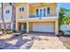 Charming yellow two-story home with balcony, turquoise door, brick driveway, and palm trees at 145 50Th St, Holmes Beach, FL 34217