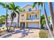 Charming yellow two-story home with balcony, turquoise door, brick driveway, and palm trees at 145 50Th St, Holmes Beach, FL 34217